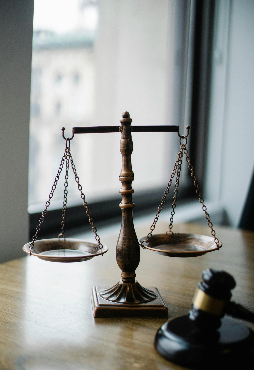 Viviana M. Breitbach – Anwältin – Das Bild zeigt einen hölzernen Hammer und die Justitia-Waage auf einem Holztisch, die üblicherweise das Rechtssystem und die Gerechtigkeit symbolisieren.